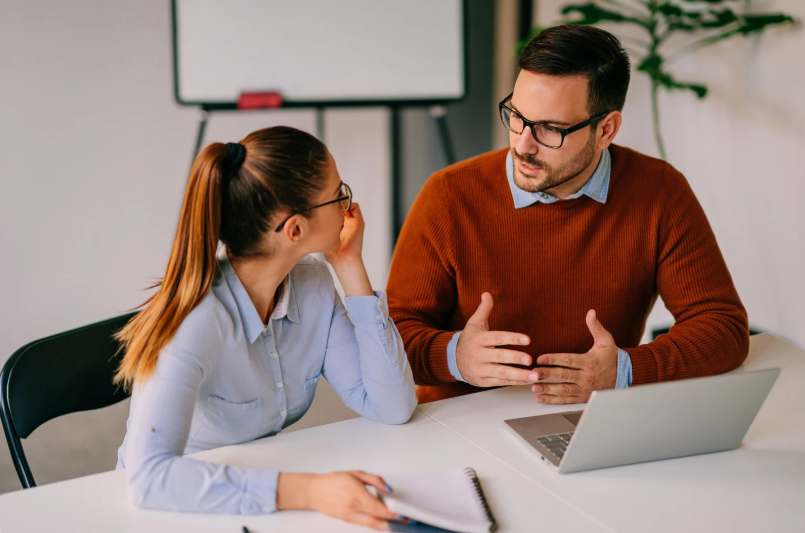 A manager engaged in a supportive one-to-one conversation with a colleague, demonstrating early intervention leadership through attentive listening and open dialogue to address team member needs before issues escalate.